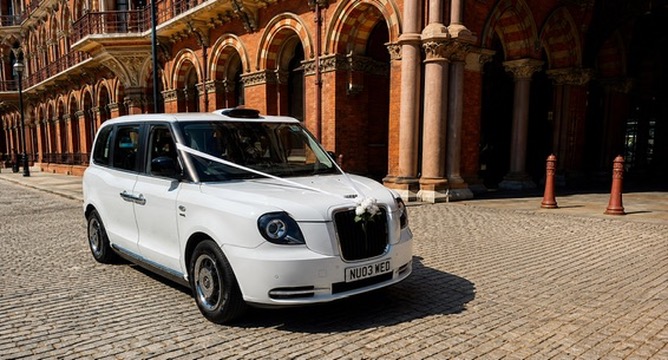 White electric TXE wedding taxi outside St Pancras, London