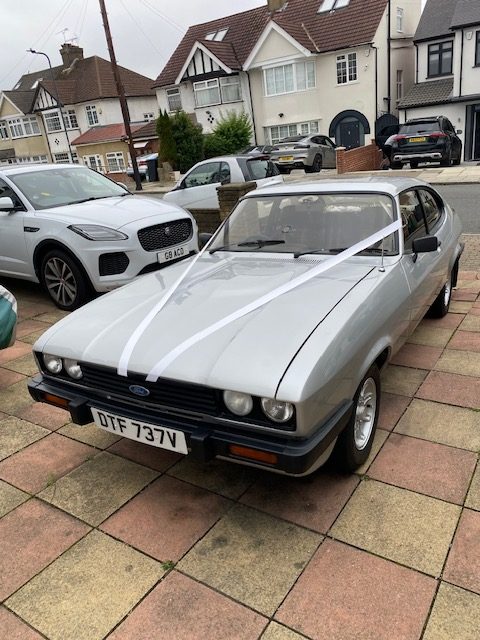 Silver Ford Capri 3.0 S wedding car dressed with white ribbons