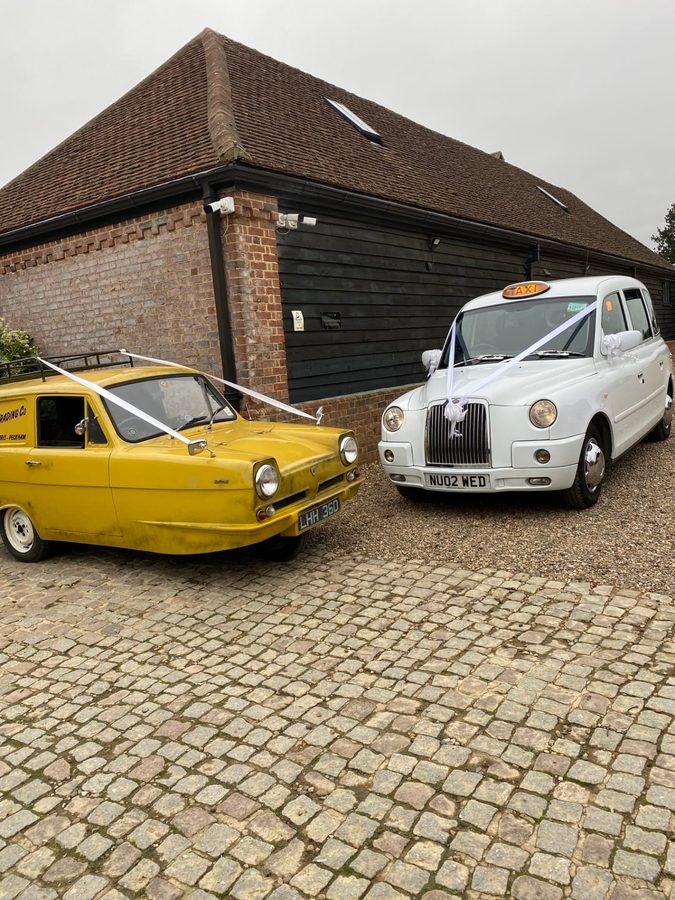 White TX4 wedding taxi and yellow Trotter van paired together at a country venue