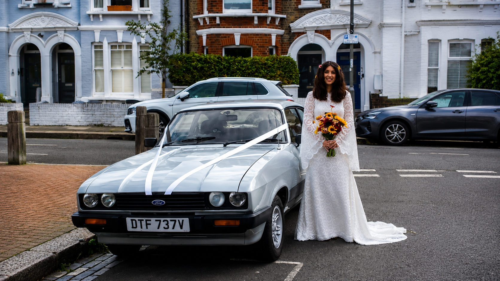 Bride beside the silver Ford Capri 3.0 S dressed with white ribbons