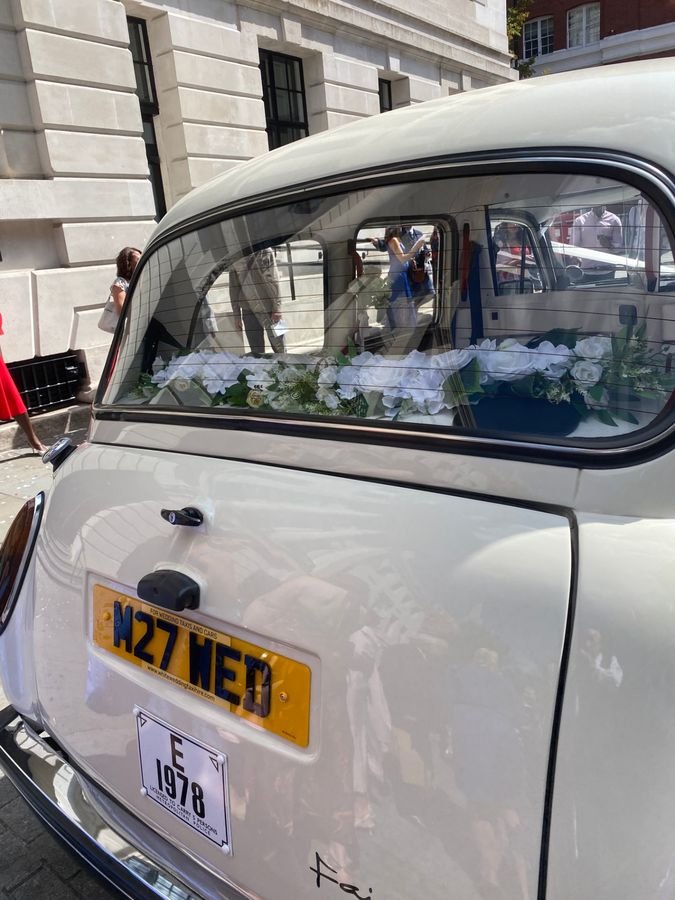 Rear of the Classic Fairway wedding taxi with silk roses on the parcel shelf, M27 WED