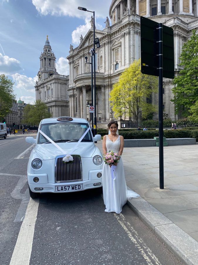 Bride with white TX4 wedding taxi at St Paul's Cathedral