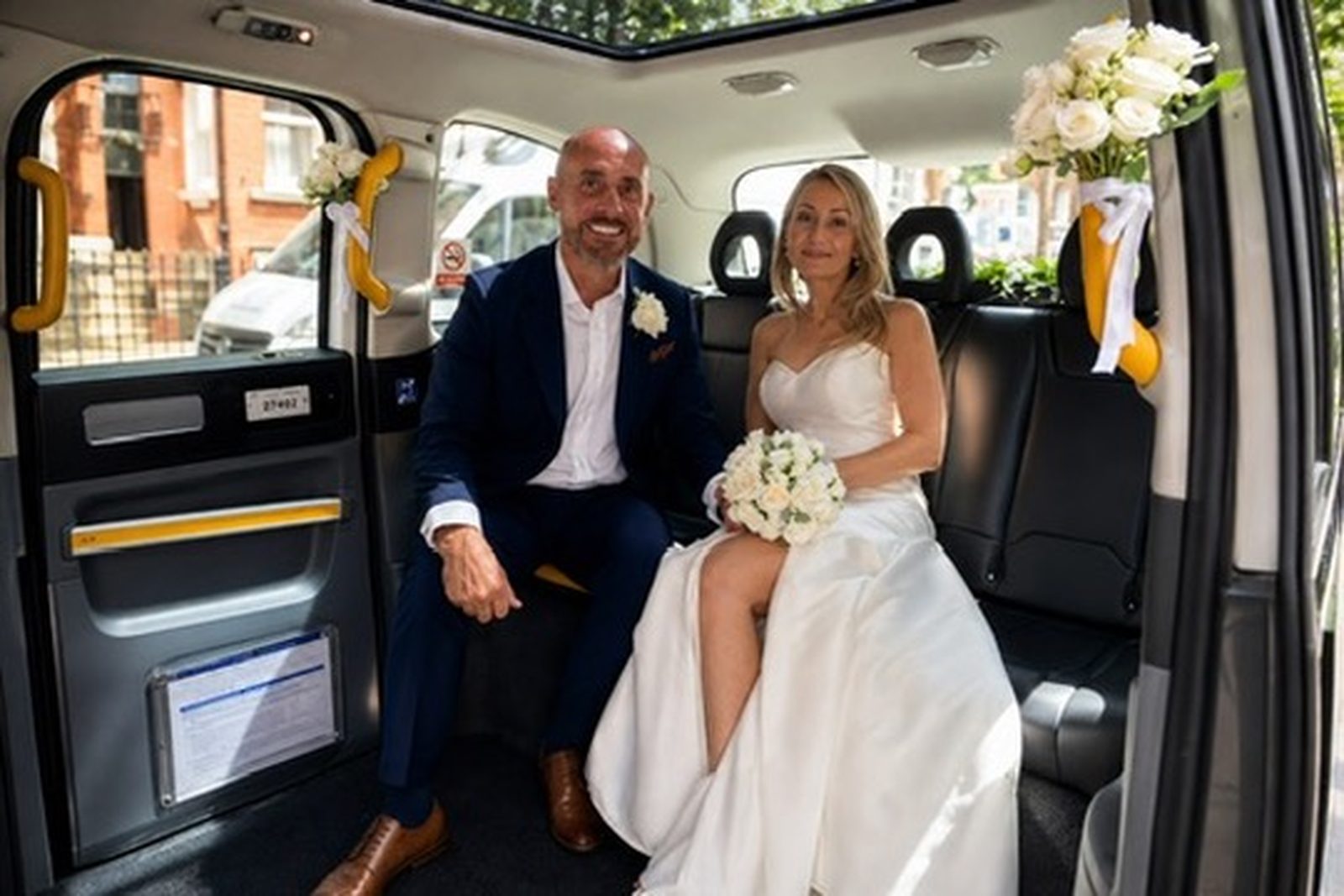 Bride and groom seated in the rear of the electric TXE wedding taxi