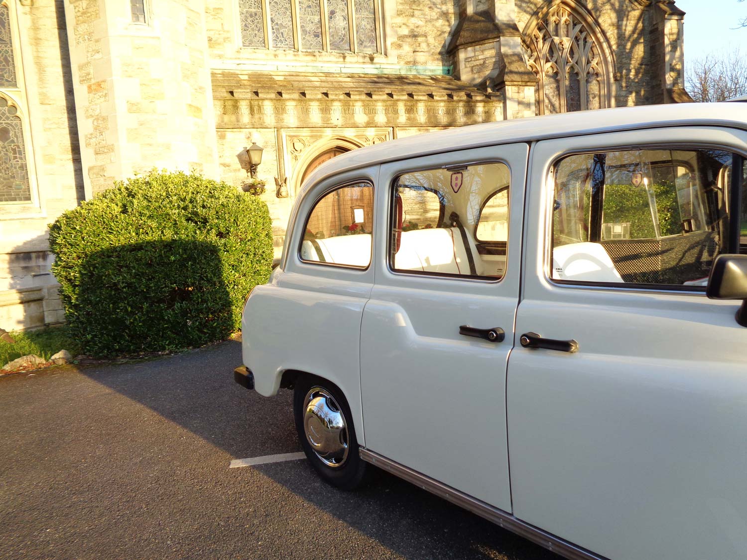 Close view of a white wedding taxi beside the church