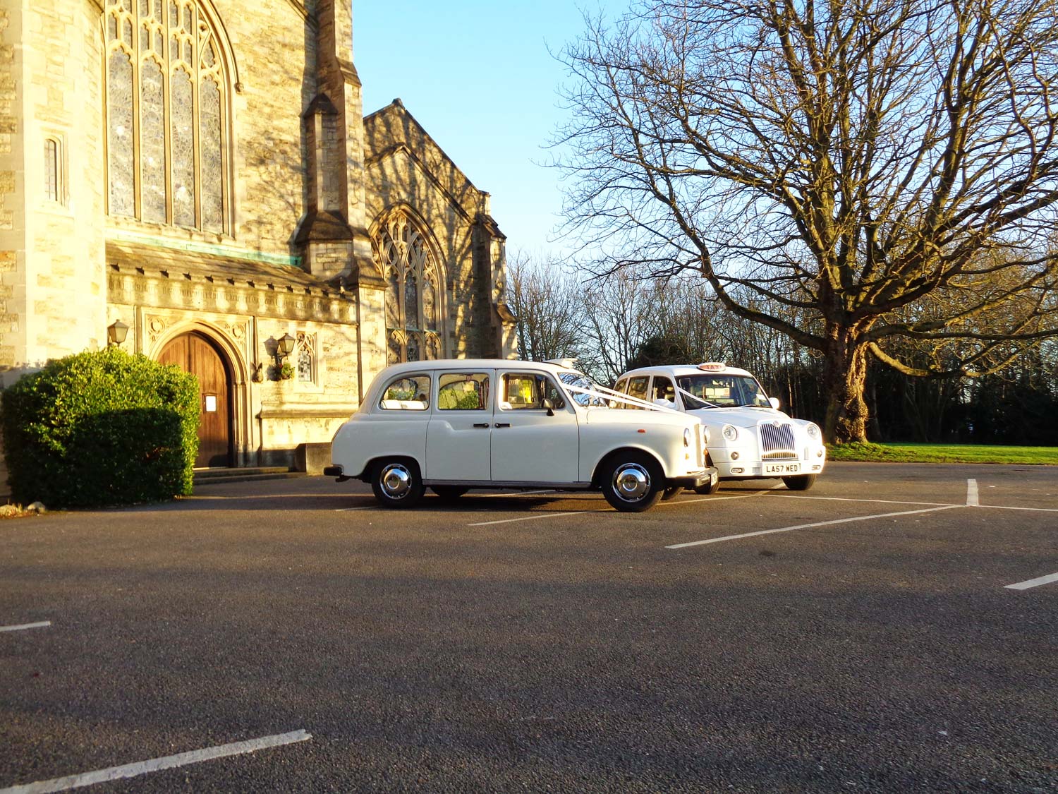 Pair of white wedding taxis at the church door