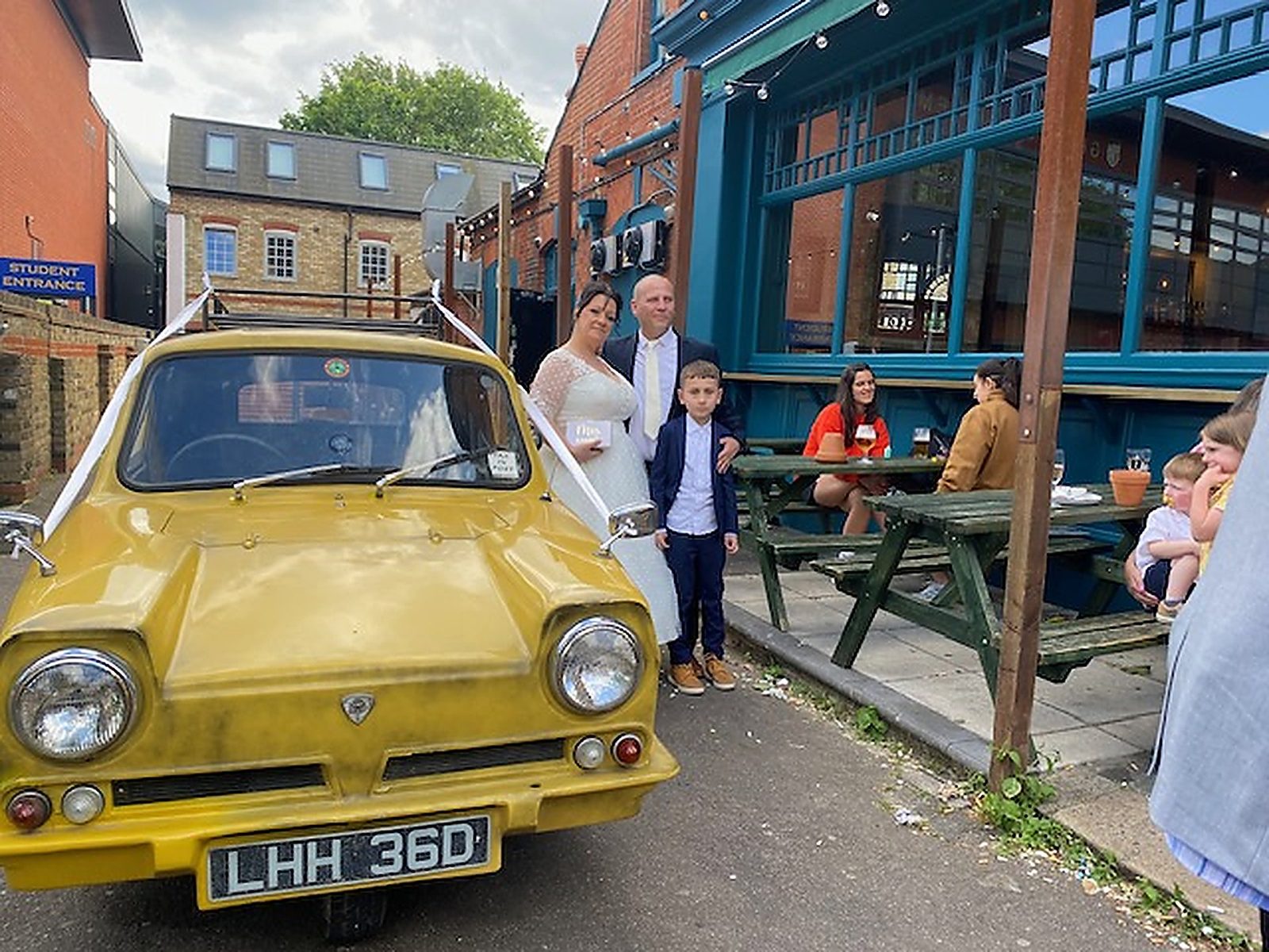 Bride, groom and page boy beside the wedding car